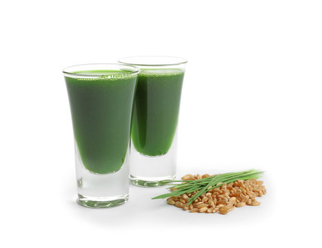 Wheat grass shots and grain on white background