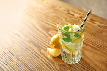 Cold fresh mojito with mint and lemon slices in glass on wooden table