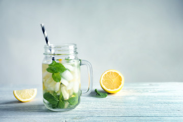 Cold fresh mojito with mint and lemon slices in mason jar on wooden table