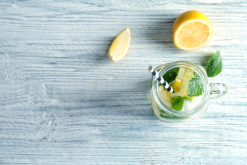 Cold fresh mojito with mint and lemon slices in mason jar on wooden background