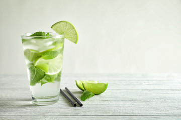 Cold fresh mojito with mint and lime slices in glass on wooden table