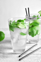 Cold fresh mojito with mint and lime slices in glass on wooden background