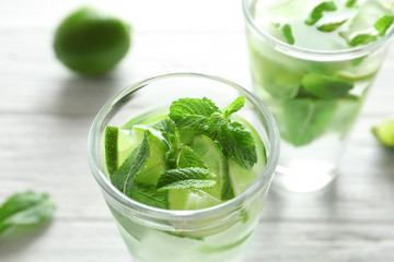 Cold fresh mojito with mint and lime slices in glass on wooden background