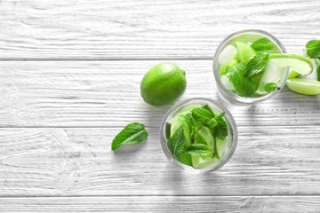 Cold fresh mojito with mint and lime slices in glasses on wooden background