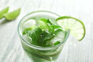 Cold fresh mojito with mint and lime slices in glass on wooden background
