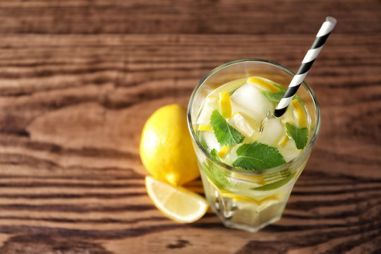 Cold fresh mojito with mint and lemon slices in glass on wooden background