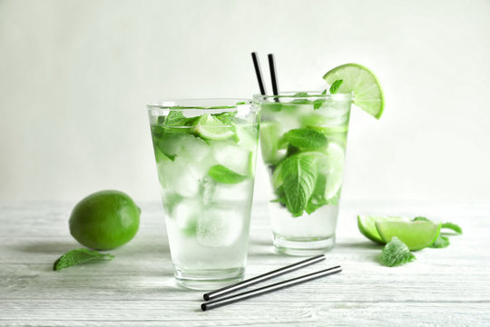 Cold fresh mojito with mint and lime slices in glasses on wooden background