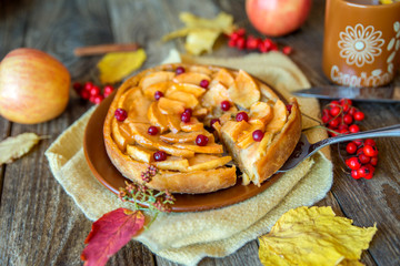 Apple pie on a wooden texture with red berries