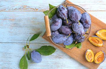 Basket with ripe plums on wooden background