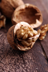 Walnut kernels and whole walnuts on rustic old wooden table.