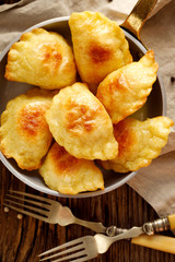 Baked dumplings stuffed with curd cheese and potatoes in a pan on wooden rustic table, nutritious...