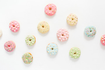 Colorful donuts on white background. Flat lay, top view minimal pattern.