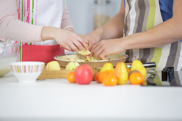 young smiling couple cooking pie at the kitchen at home