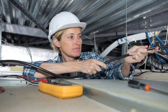 female technician checking the air conditioning in the ceiling
