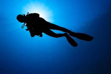 Fototapeten Silhouette of a SCUBA diver with sunburst behind © whitcomberd
