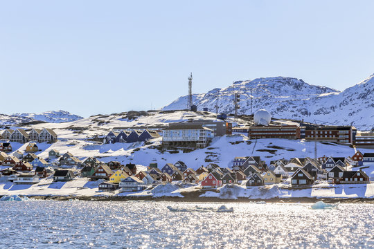 Rows of colorful Inuit houses along the fjord with snow mountains in the background, Nuuk city, Greenland