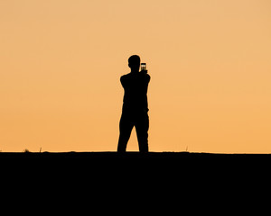 A man taking selfie on sunset