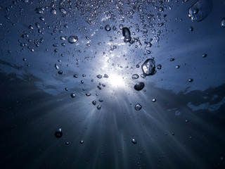 Underwater bubbles going up while sun rays going down