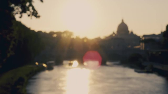 Blurred video of a wonderful view of sunset coming down behind the great St. Peter's Basilica in Rome, Italy. Video shot from a bridge over the Tiber river.