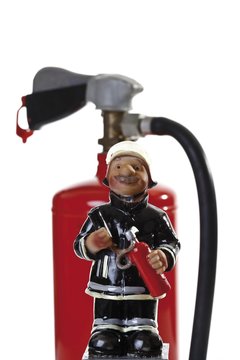 Miniature figure of a fire fighter in front of a fire extinguisher