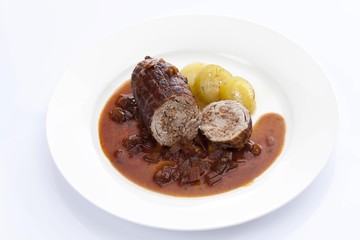 Braised pork roulade stuffed with minced meat, onion sauce and stewed cucumber on a porcelain plate