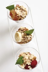 Muesli with yoghurt in a small glass jar, raspberries, sliced banana, grapes, mint leafs