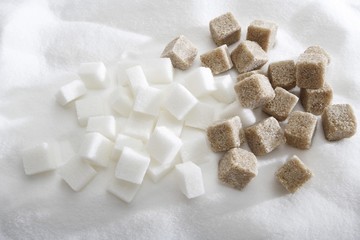Brown and white sugar, sugar cubes on pile of sugar