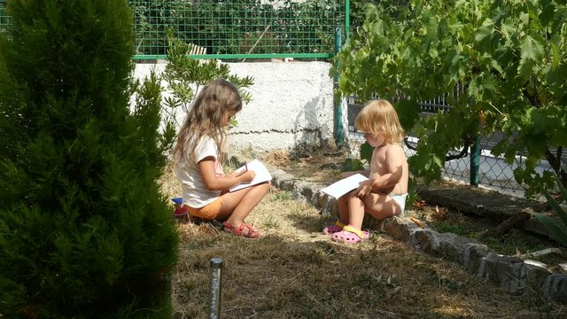 Children Playing In The Yard. Two Kids Sitting And Playing With Note Books