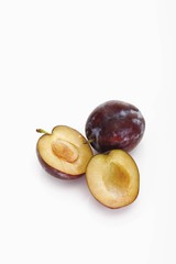 Two plums, one of them halved