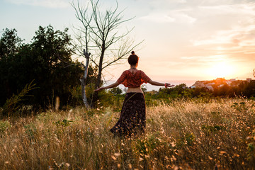 A woman opens her hands under the sunrise in a radiant field. People freedom style.
