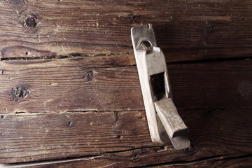 Old wood plane hanging on a rustic wooden wall