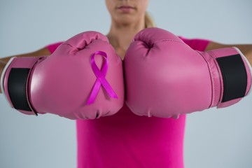 Mid section of woman with boxing gloves and pink ribbon