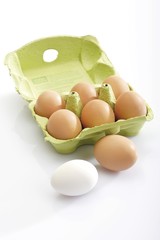 Brown eggs in a carton and a white one