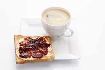 Porcelain plate with a cup of coffee and toast with strawberry jam