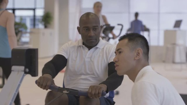 Man working out at the gym being supervised by fitness instructor