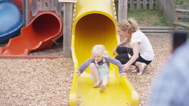  Happy little girls coming down slide at adventure playground