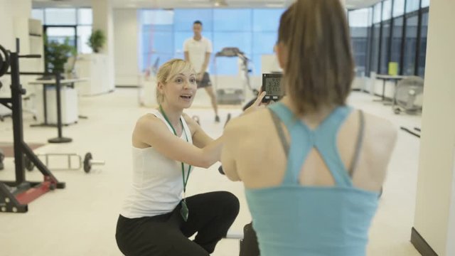 Personal trainer watching over clients, working out in modern gym