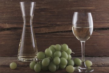 White wine with grapes in front of a wood background