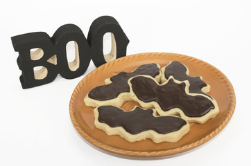 Black and white homemade Halloween bat cookies on an orange plate and a black wooden 