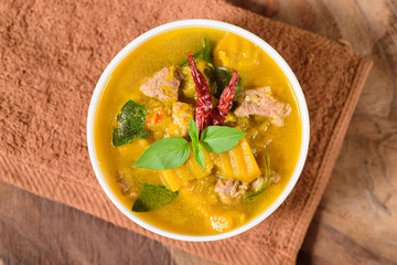 Thai food.Spicy pumpkin soup with pork in a bowl on brown fabric and wooden background.Top view of food