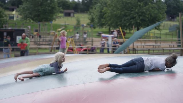  Little girls having fun, jumping on inflatable at outdoor activity centre