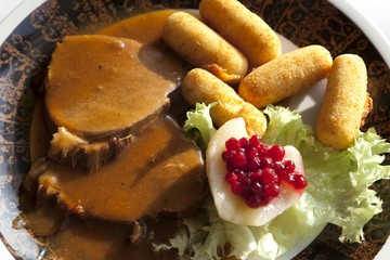Roast pork with sauce, potato croquettes and pear with cranberries