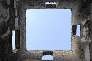 Blue sky above four walls of a ruined building without a roof