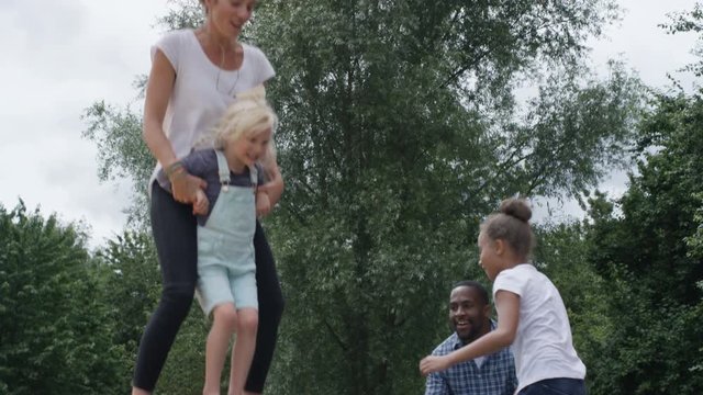  Happy mixed race family having fun, jumping on inflatable at activity centre