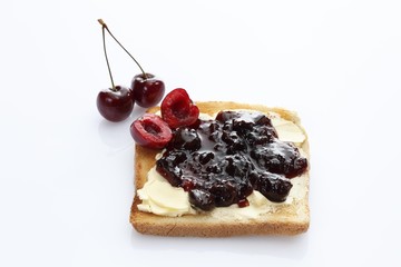 Slice of toast, toasted slice of bread, with cherry jam and chrries