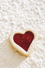 Heart-shaped short pastry biscuit, jam-filling, on icing sugar