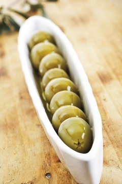 Green olives in a sagger on a wooden board