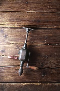 Old Crank Drill Hanging On A Rustic Wooden Wall