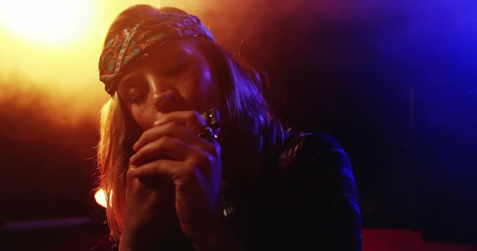 Woman playing harmonica at nightclub 