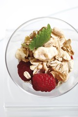 Muesli with yoghurt in a small glass jar, raspberries, mint leafs